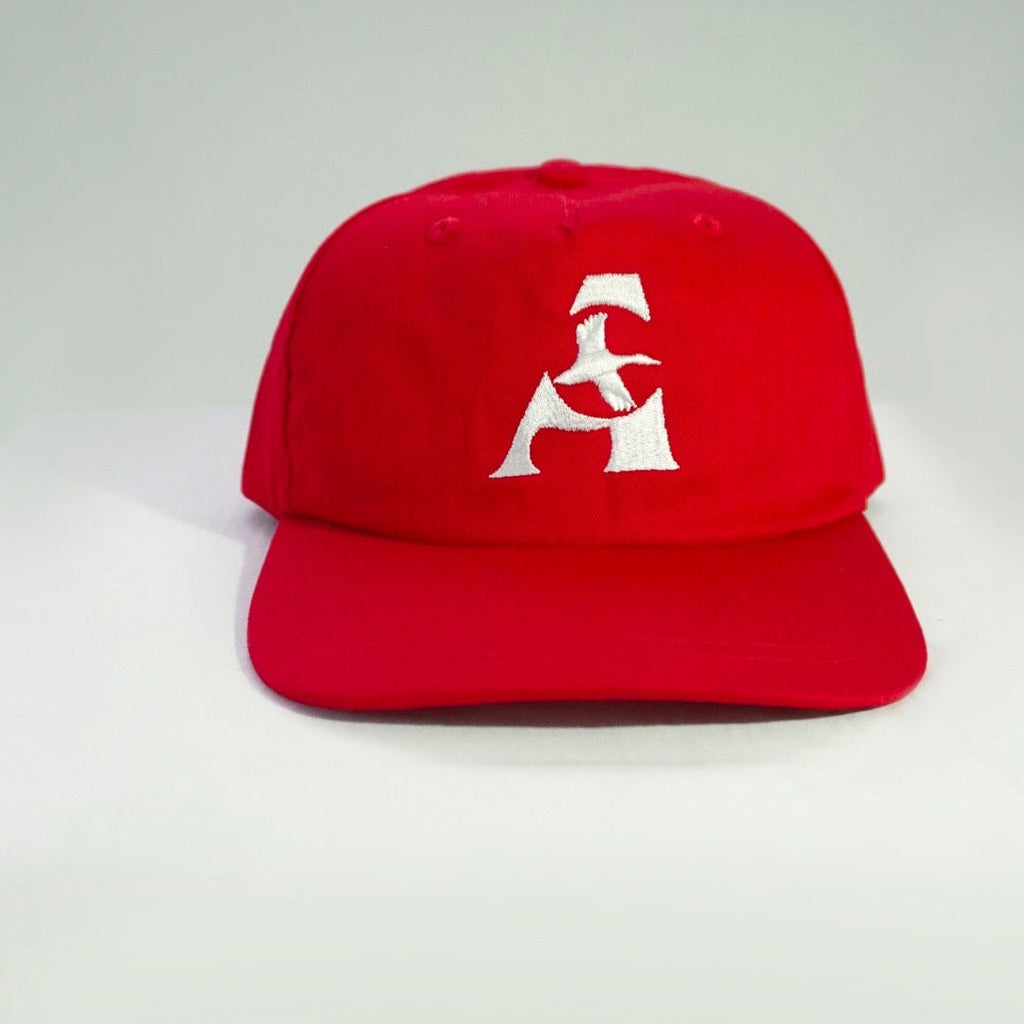 A bright red baseball cap with a white embroidered stylized 'A' logo on the front, set against a neutral light gray background.